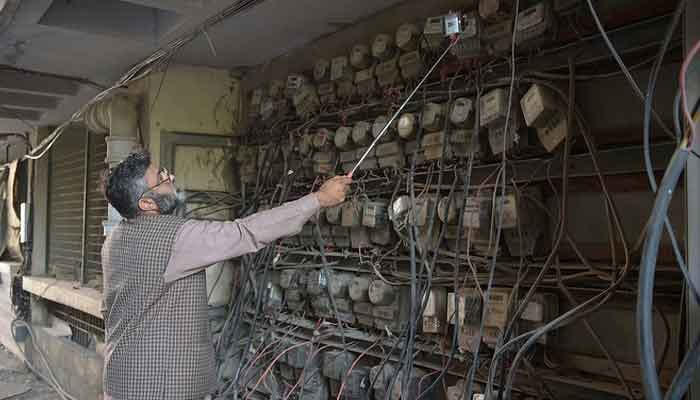 An employee of Islamabad Electric Supply Company takes a meter reading with his smartphone at a commercial building in Islamabad. — AFP/File