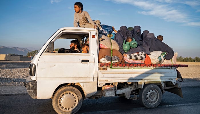 This photograph on November 12, 2023, shows Afghan refugees with their belongings sitting atop a truck as they head from a makeshift camp near the Afghanistan-Pakistan Torkham border to Jalalabad. — AFP
