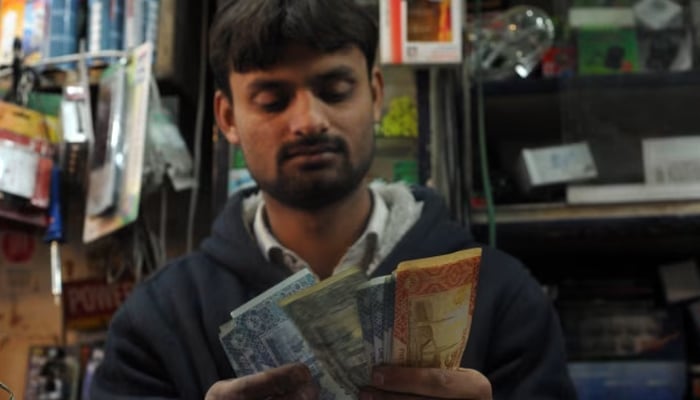 A Pakistani shopkeeper counts money at a store in Islamabad. — AFP/File