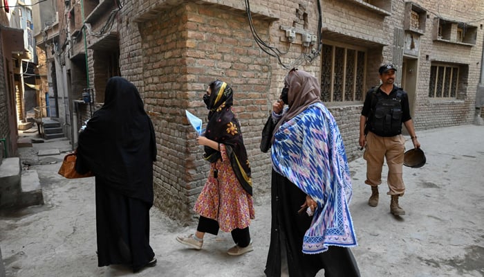 Health workers visit a residential area along with a security personnel during a polio vaccination campaign in Peshawar on May 22, 2023. — AFP