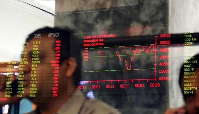 An undated image of investor speaking on the phone in the background of the digital stock board. — AFP/File