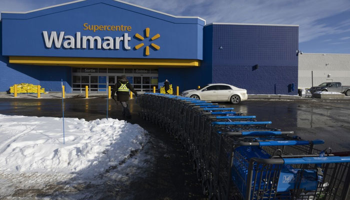 A worker pulls shopping carts outside a Walmart store in Montreal, Quebec. — Bloomberg