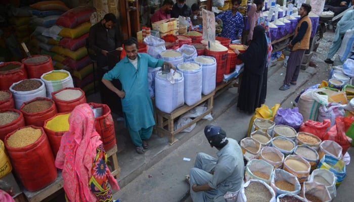 People buy pulses and grains at a wholesale market in Karachi. — AFP/File