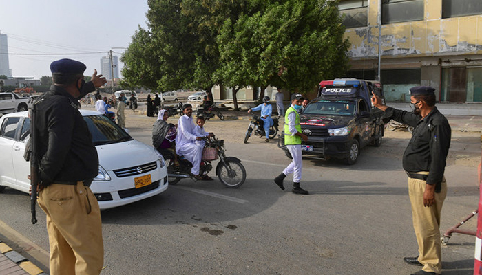 This image shows Sindh Police officials gesturing at a car on a road. — AFP/File