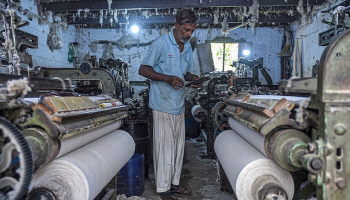 An employee works on a loom at a fabric factory in Karachi. — AFP/File