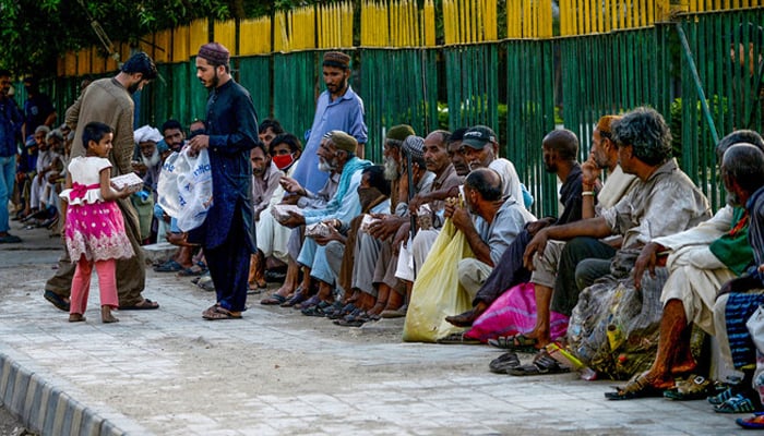 In this file photo, men distribute food to people during a government-imposed anti-coronavirus lockdown in Karachi. — AFP