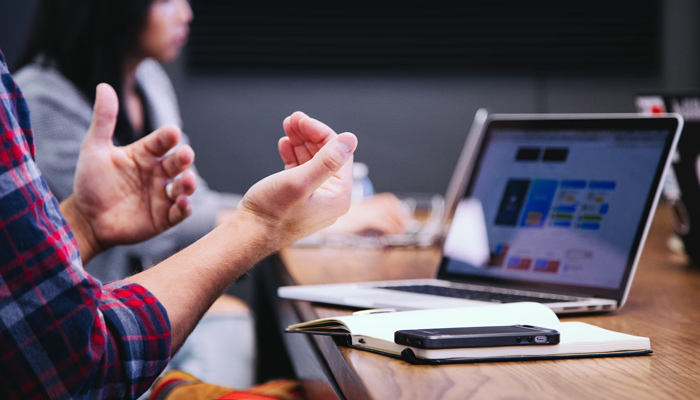 A representational image shows a person gesturing while talking in a professional setting. — Unsplash/File