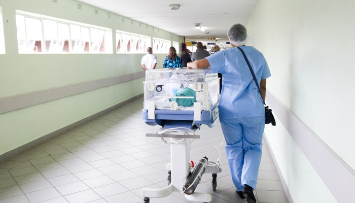 A representational image shows a hospital official moving a cart. — Unsplash/File