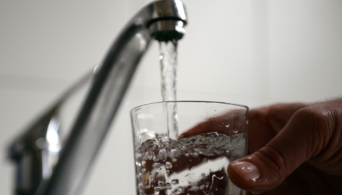This representational image shows a person pouring a glass of water from a tap. — AFP/File