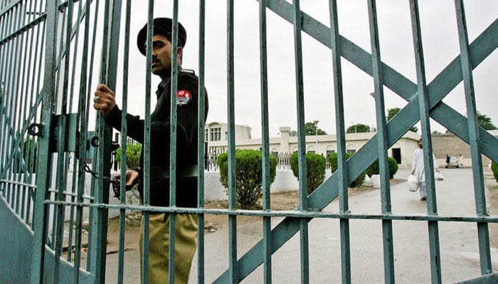 A policeman closes the main gate of a jail. —AFP/File