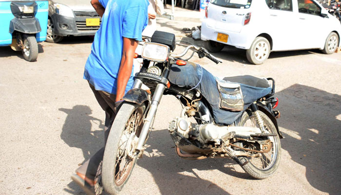 Man carries a motorcycle from a street in Karachi on September 8, 2023. — PPI