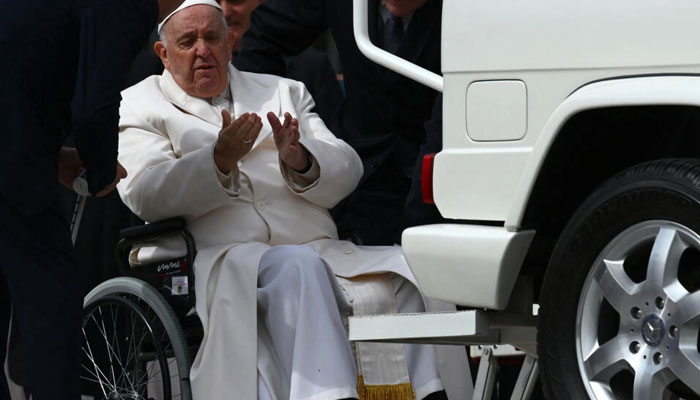 Pope Francis speaks with aides prior to being helped into the “popemobile” from his wheelchair following the weekly general audience at St. Peters square in The Vatican, March 29, 2023. —AFP