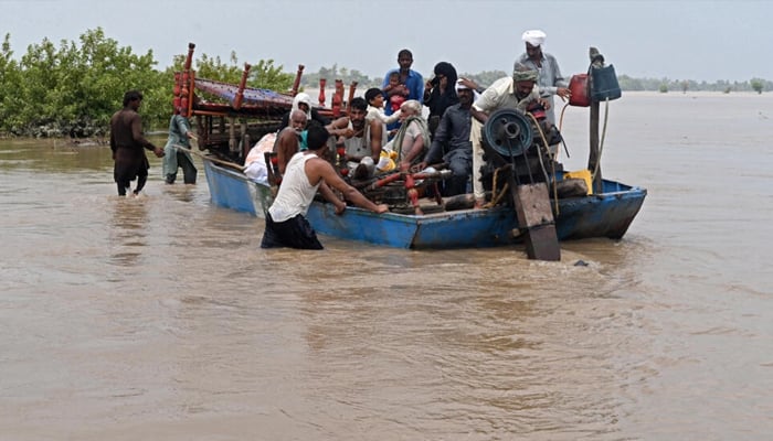People with their belongings wade through the flood-affected area of Chanda Singh Wala village in the Kasur district on August 22, 2023. — AFP
