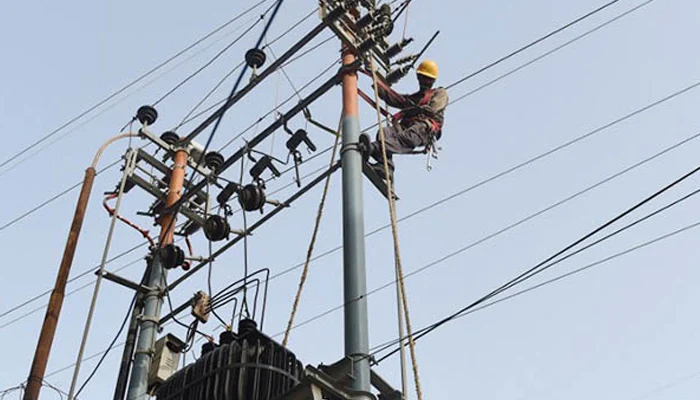 A worker can be seen working on an electricity pole. — AFP/File