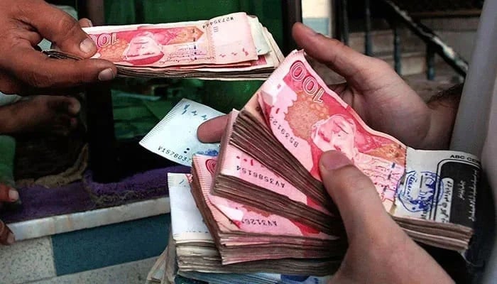 A person can be seen holding notes of Pakistani currency Rupee in their hands. — AFP/File