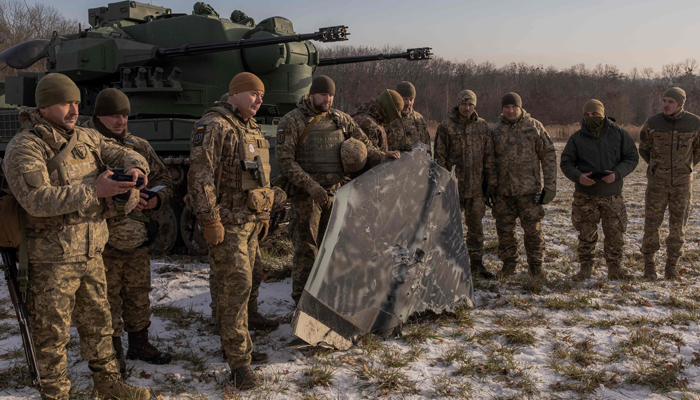 Ukrainian soldiers pose for a photo with an allegedly downed painted black Russian launched drone next to a German Gepard anti-aircraft-gun tank, in the outskirts of Kyiv, on November 30, 2023. — AFP