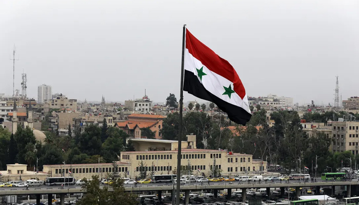 A Syrian flag flies near a bus station in the Baramkeh neighbourhood of the capital Damascus. — AFP/File