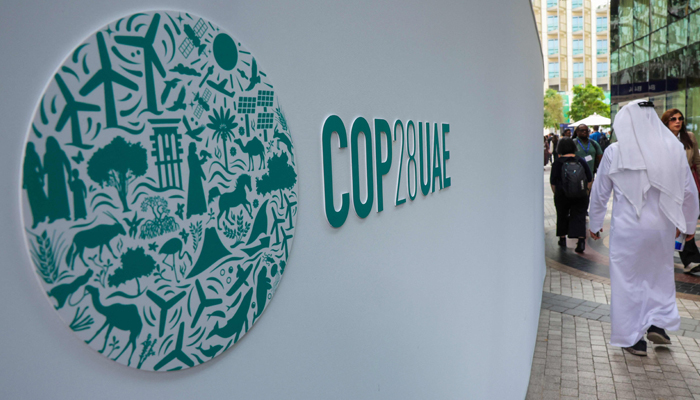 Participants walk past a COP28 sign at the Expo City during the United Nations climate summit in Dubai on December 3, 2023. — AFP