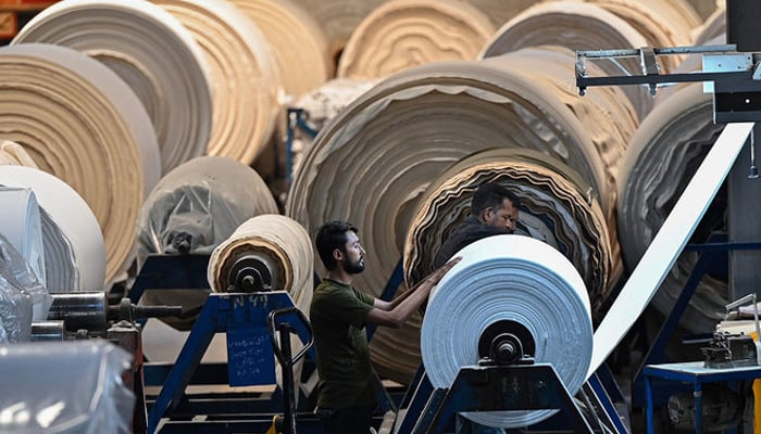 This picture shows a worker operating a machine preparing fabric in Lahore. — AFP/File