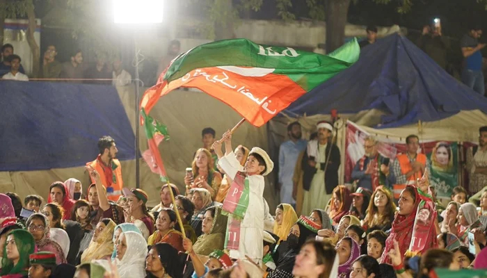 Pakistan Tehreek-e-Insaf supporters can be seen in this picture with a child raising the flag of PTI in this image released on April 25, 2023. — Facebook/Imran Khan