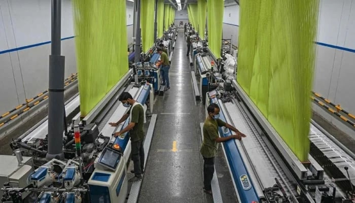 A worker operates a machine preparing fabric at the Kohinoor Textile Mills in Lahore on July 20, 2023. — AFP