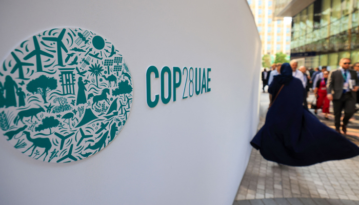 People walk past a COP28 sign at the Expo City during the United Nations climate summit in Dubai on December 5, 2023. — AFP