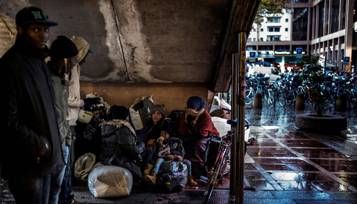 People prepare to sleep under stairs in a street in Lyon, central-eastern France .— AFP