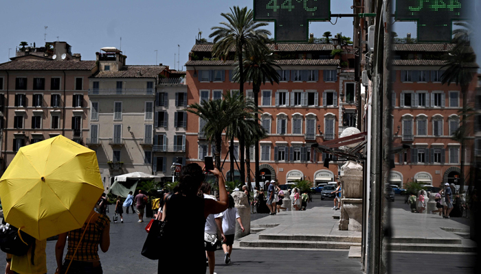 Pedestrians walk under a pharmacys sign indicating the current outside temperature near the Scalinata di Trinita dei Monti (Spanish Steps) in Rome on July 17, 2023. — AFP