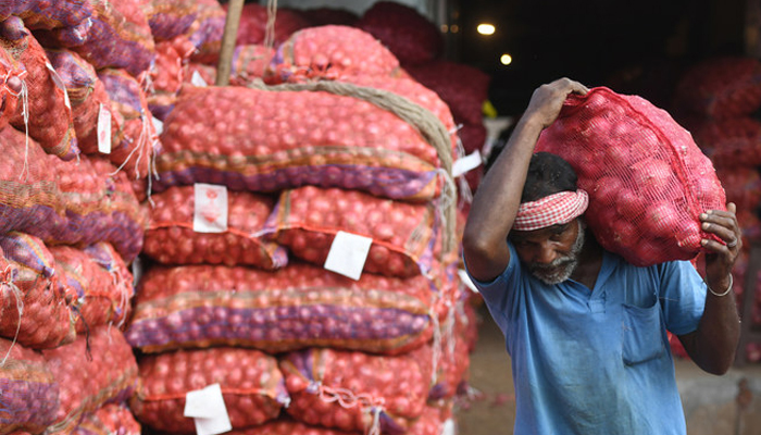 An Indian labourer carries a sack of onions on his shoulder at a wholesale market in Chennai. — AFP/File