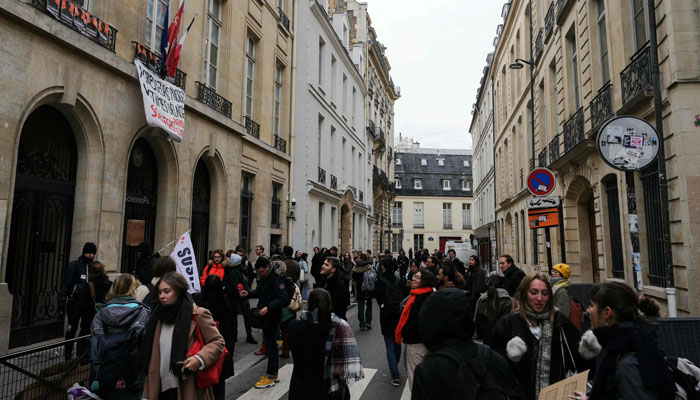 Protestors stand in front of a banner reading during a blocking protest at the Sciences Po University to demand the resignation of its director in Paris, on December 7, 2023. — AFP