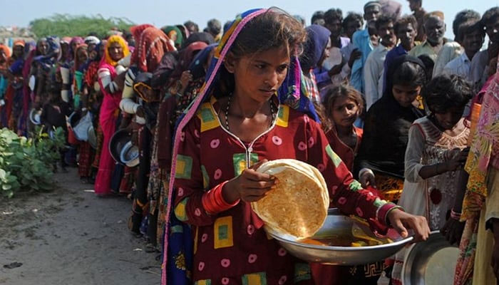 Internally displaced people gather to receive free food near their makeshift camp in the flood-hit Chachro of Sindh province on September 19, 2022. — AFP