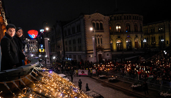 Ali Rahmani (L) and Kiana Rahmani, children of the 2023 Nobel Peace Prize laureate Narges Mohammadi stand on the balcony during a torchlight procession organized by The Norwegian Peace Council for the winner of the Nobel Peace Prize, Narges Mohammadi, at the Grand Hotel in central Oslo on December 10, 2023. — AFP