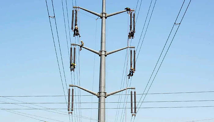 KE employees working at a high-tension electricity pylon located in Karachi on Tuesday, October 12, 2021. — PPI