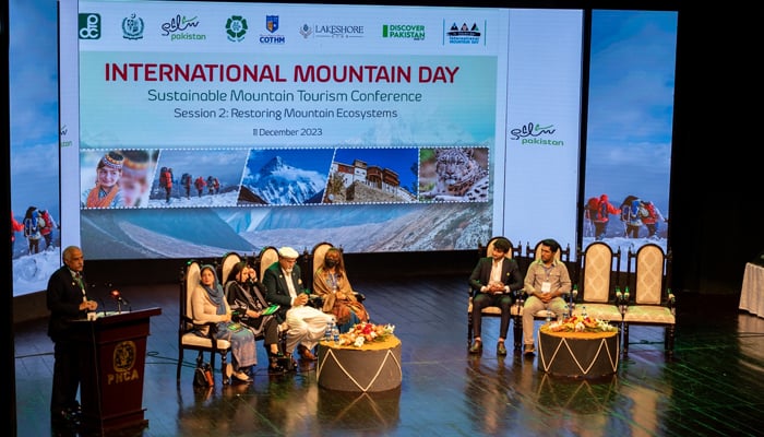 This image shows a speaker addressing the audience as people sit on the stage during International Mountain Day on December 11, 2023. — Facebook/Pakistan Tourism Development Corporation (PTDC)