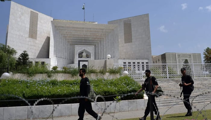 Supreme Court building can be seen in the background of the security personnel as they walk by. — AFP/File