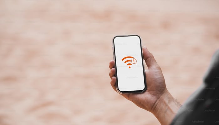 This representational image shows a person holding a mobile phone with a signal logo appearing on the screen. — Unsplash/File