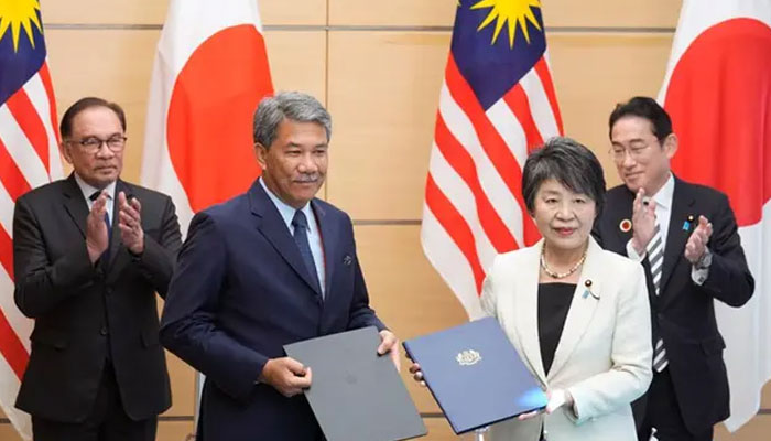 Japans Prime Minister Fumio Kishida (R) and Malaysias Prime Minister Anwar Ibrahim (L) applaud as Japans Foreign Minister Yoko Kamikawa (2nd R) poses with her Malaysian counterpart Mohamad Hassan (2nd L) after a signing ceremony at the prime ministers official residence in Tokyo on December 16, 2023. AFP