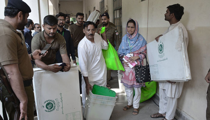 Polling workers receive polling-related materials at Government Post Graduate College Samnabad. — APP/File
