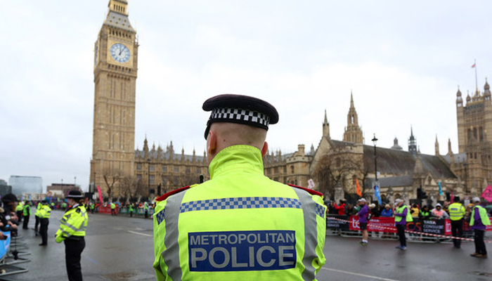 An officer in the Metropolitan Police force stands on duty as competitors run past the Palace of Westminster. — AFP/File