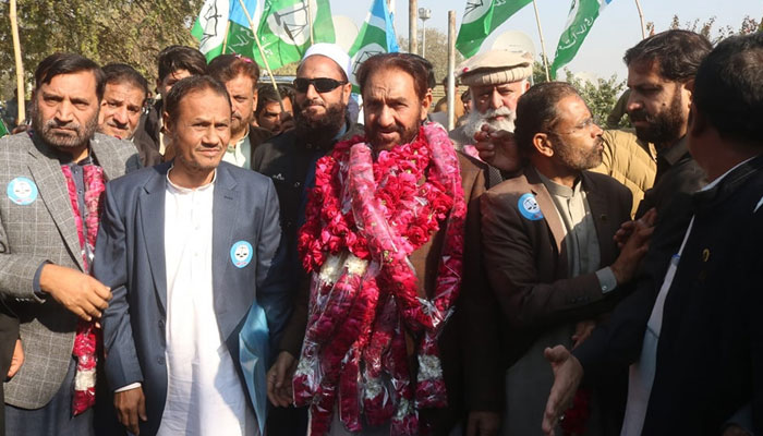 Ex-MNA and central naib ameer of JI, Mian Muhammad Aslam (C) stands with party workers after filing nomination papers on December 21, 2023. — Facebook/Jamaat-e-Islami Islamabad