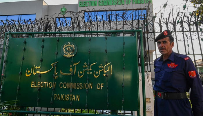 A security guard stands near the ECP sign board in Islamabad. — AFP/File