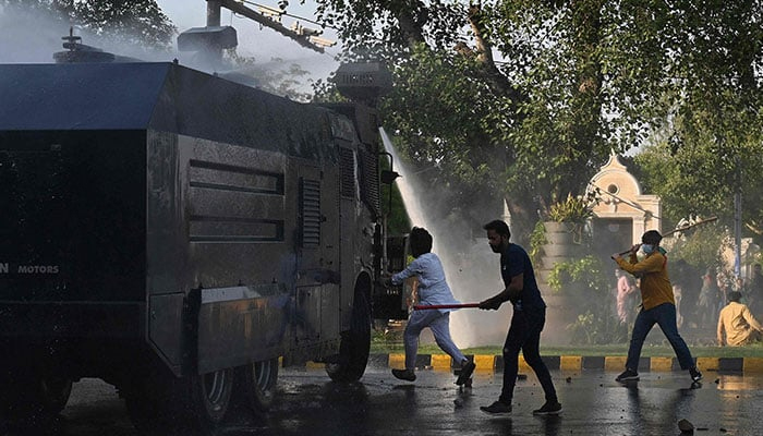 People hit a police water cannon vehicle during a protest against the arrest of Imran Khan in Lahore on May 9, 2023. —  AFP