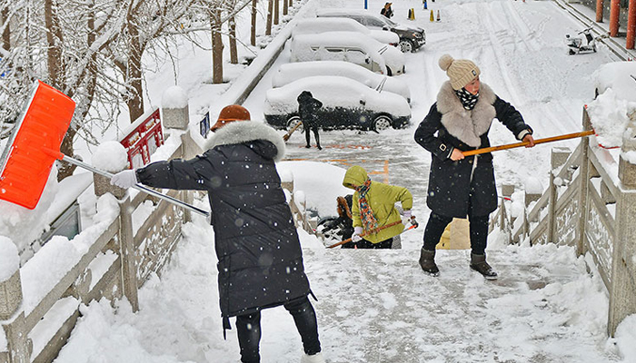 People shovel snow from an overpass after heavy snowfall in Yantai, China eastern Shandong province, on December 21, 2023. — AFP