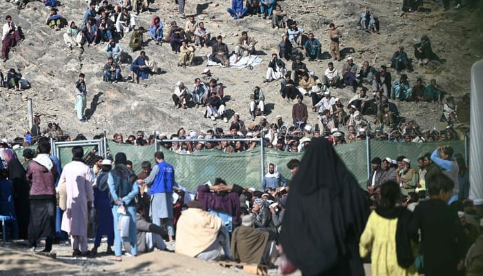 Afghan refugees sit on a hilltop outside the IOM office as they wait for registration upon their arrival from Pakistan near the Torkham border in Nangarhar on November 12, 2023. — AFP
