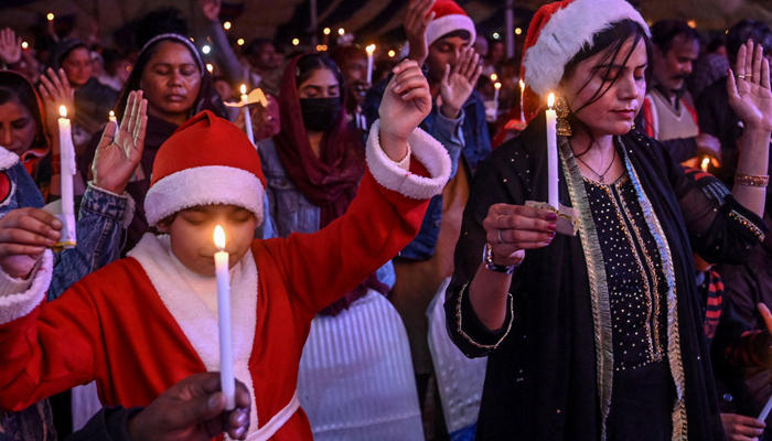 Christian devotees hold candles as they take part in a special mass ahead of Christmas, at a church in Lahore on December 20, 2023. — AFP