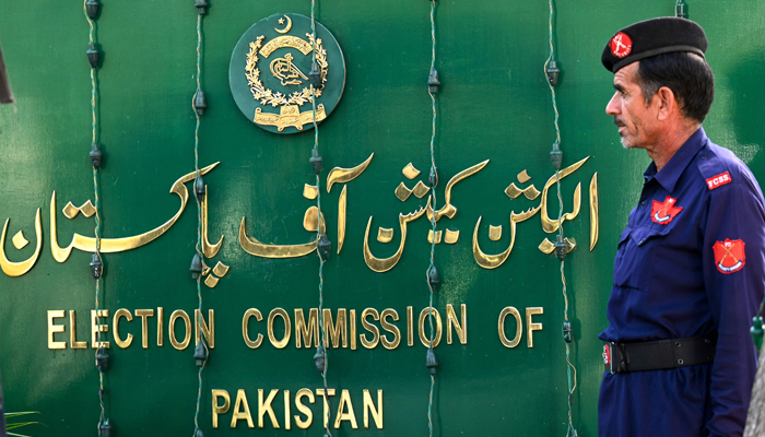 The Election Commission of Pakistan (ECP) sign board can be seen with a guard standing aside. — AFP/File