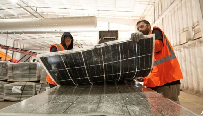 Workers push damaged solar panels into a machine to be recycled at the We Recycle Solar plant in Yuma, Arizona. — AFP