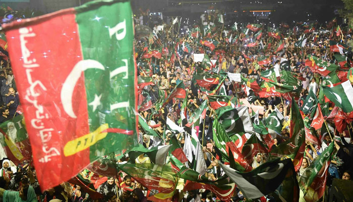 PTI supporters wave party flags as they take part in a rally in Karachi on April 10, 2022. — AFP