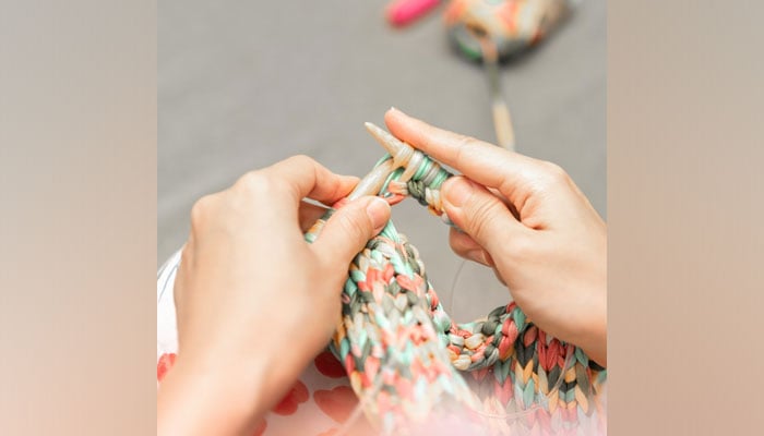 This representational image shows a woman Knitting a sweater. — Unsplash