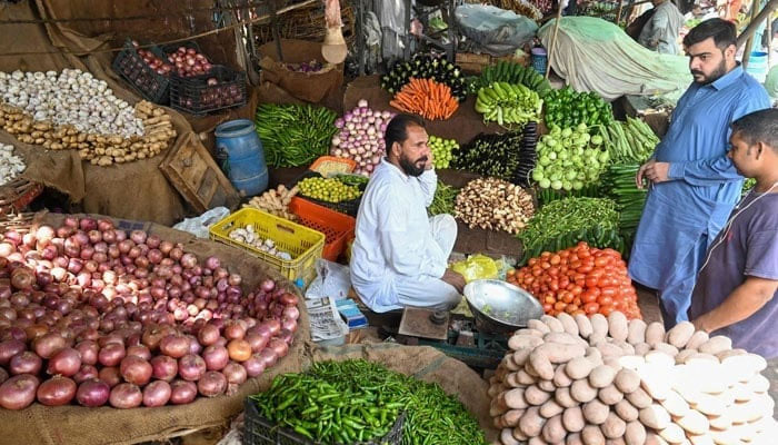 A vegetable seller can be seen interacting with a customer amid heightened inflation in Pakistan. — AFP/File